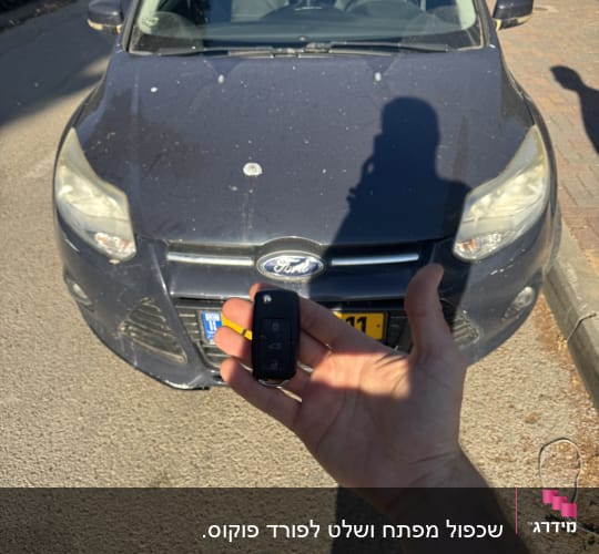 מפתח רכב מוחזק מול מכונית חונה